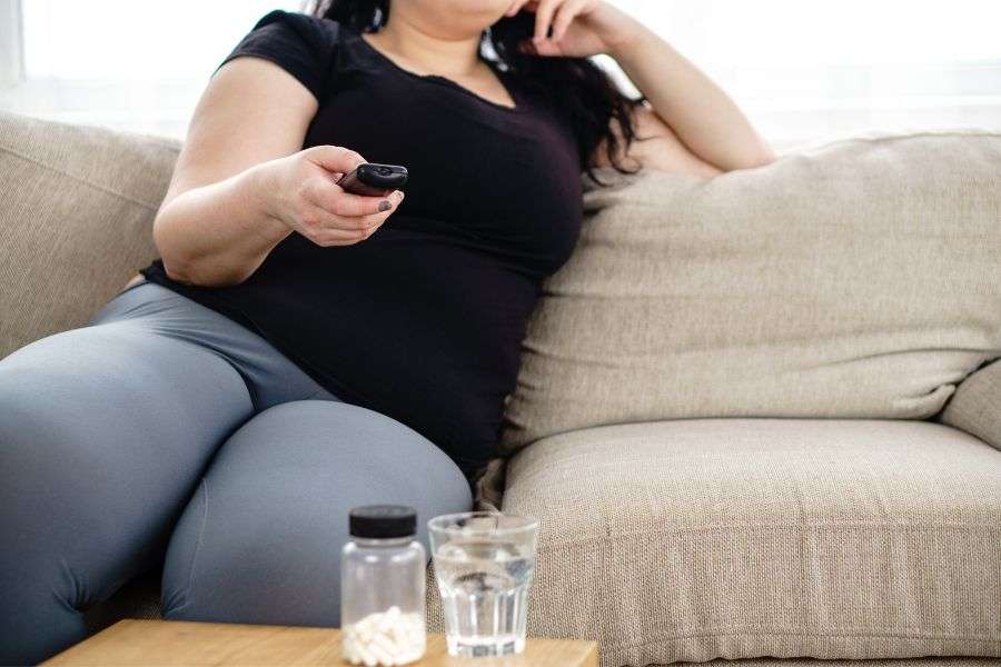 persona con obesità sul divano a guardare la tv. movement pills combatte la sedentarietà