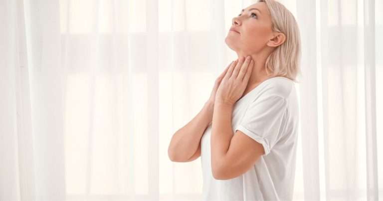 donna che si controlla il collo per la tiroide