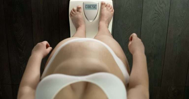 ragazza in sovrappeso che sale sulla bilancia