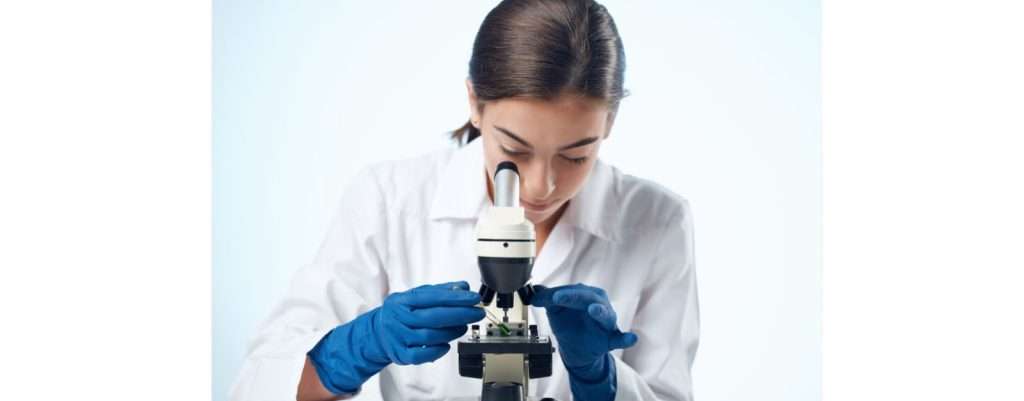 tumore al pancreas, l'importanza della ricerca scientifica. dottoressa che analizza un campione al microscopio