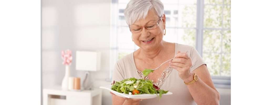 donna over che mangia un piatto di insalata