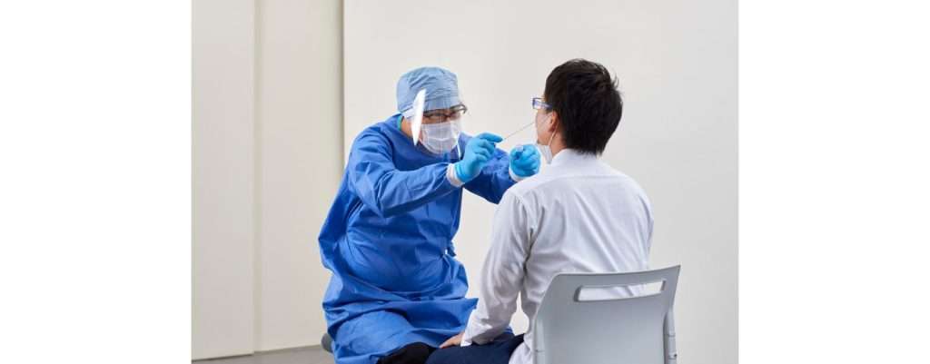 medico con mascherina che esegue tampone durante il covid