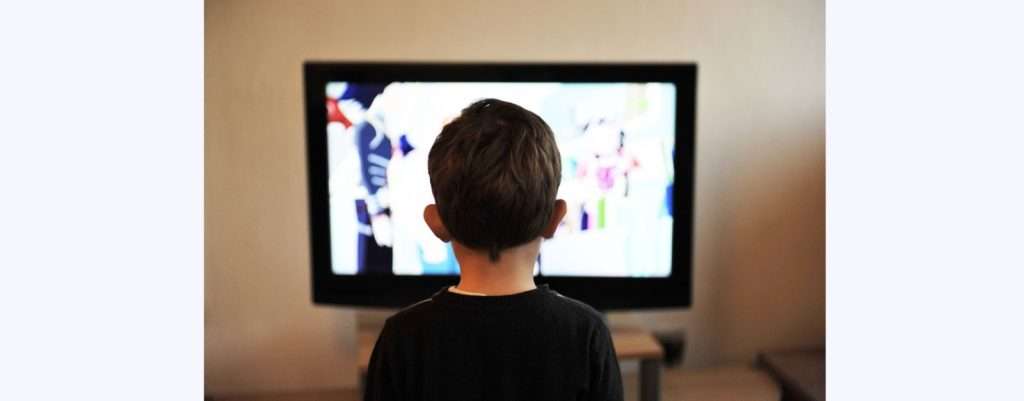 Energy drink, proposti dalla pubblicità in TV, ragazzino davanti allo schermo della tv